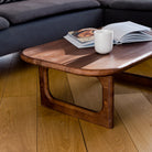 Wooden coffee table with a magazine and a white mug in a living room setting.